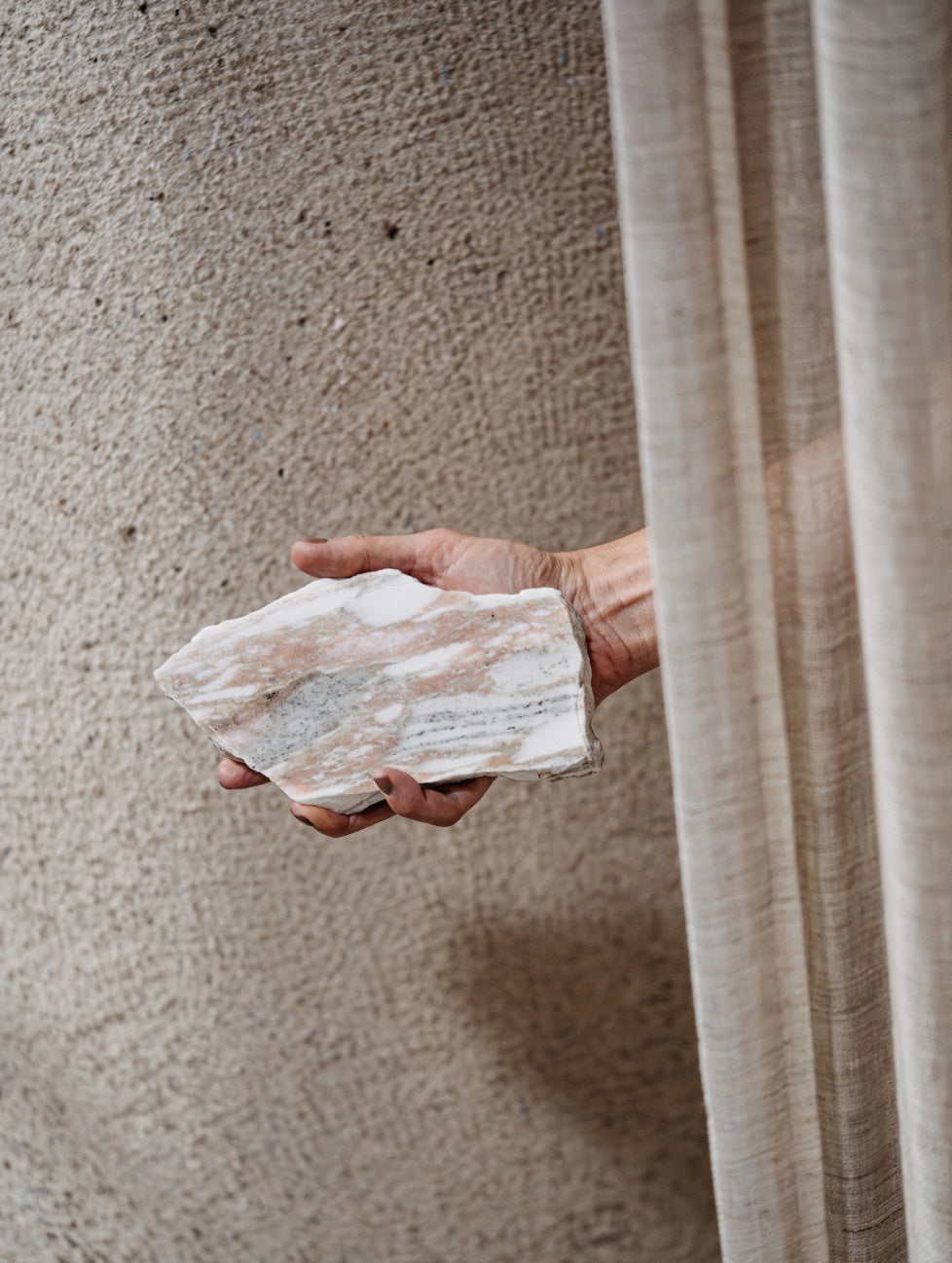 Een hand met daarin een restant van marmer, als symbool voor het duurzame karakter en recyclen van natuursteen.