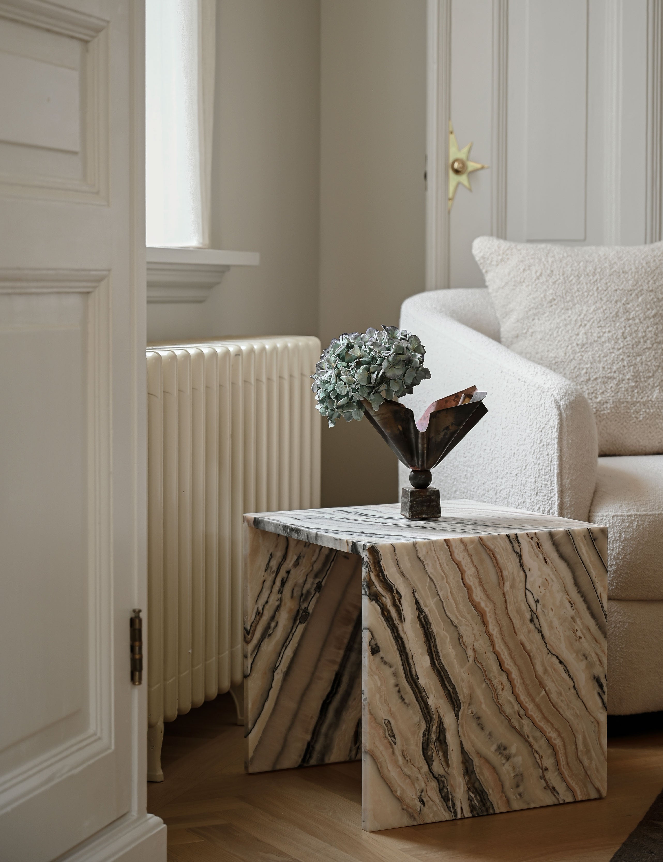 Interieur sfeerbeeld van een elegante bijzettafel of salontafel gemaakt van natuursteen. Tijdloos in kwaliteit en stijl, in een vierkante u vorm. Uitgevoerd in een unieke en exclusieve onyx: Desert Linea, opvallend met diverse tinten beige en bruin.